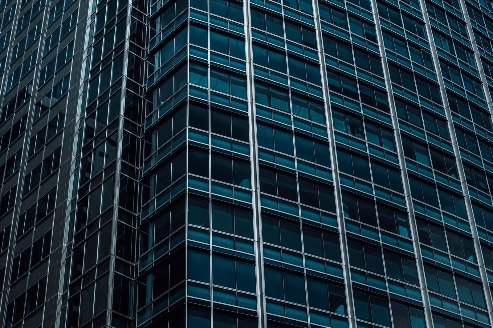 The corner of a commercial building clad in a glass curtain wall.